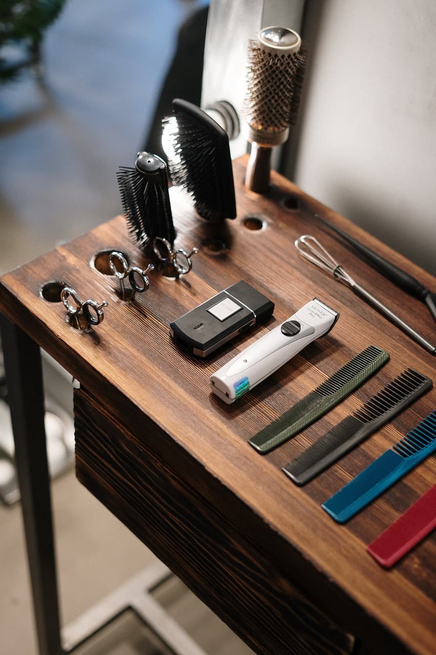 Clippers, combs and a trimmer laid out on a walnut station